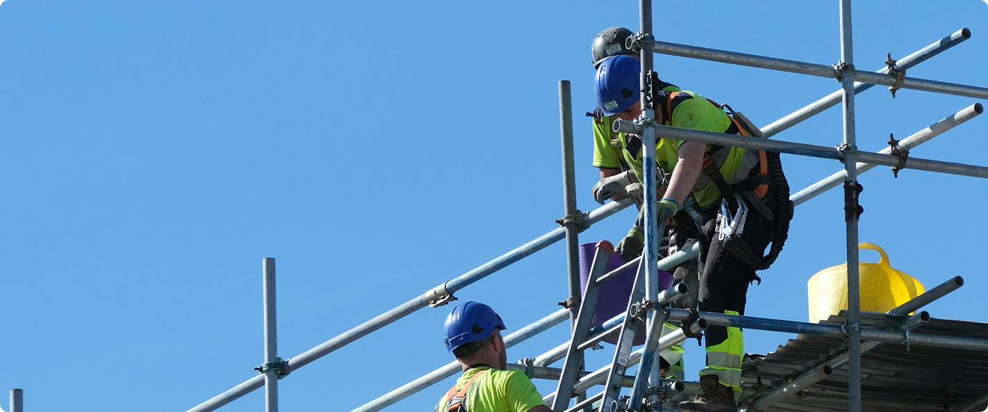 Trabajadores de construcción en andamio contra cielo azul